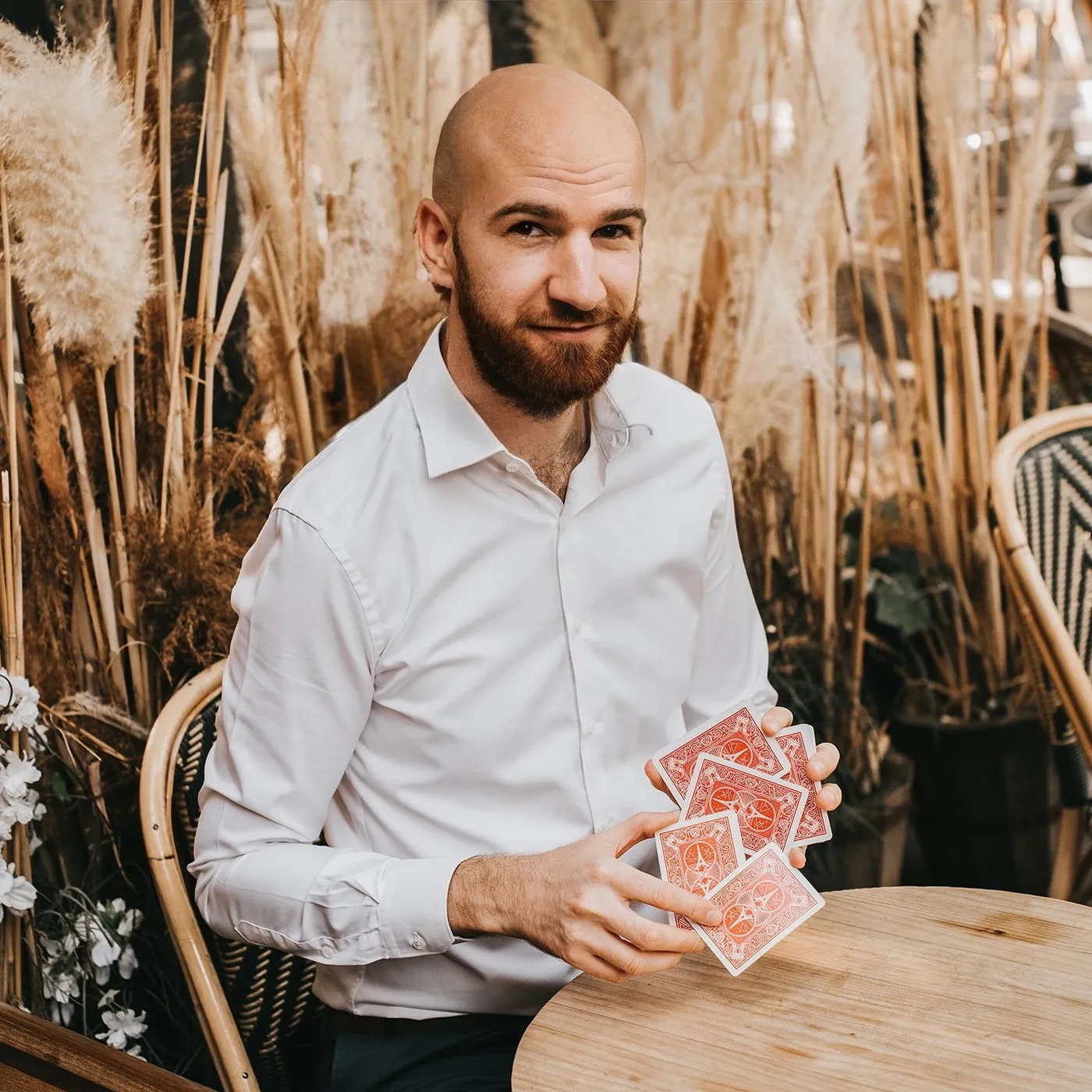 Ugo avec un H, jeu de cartes en main, en terrasse