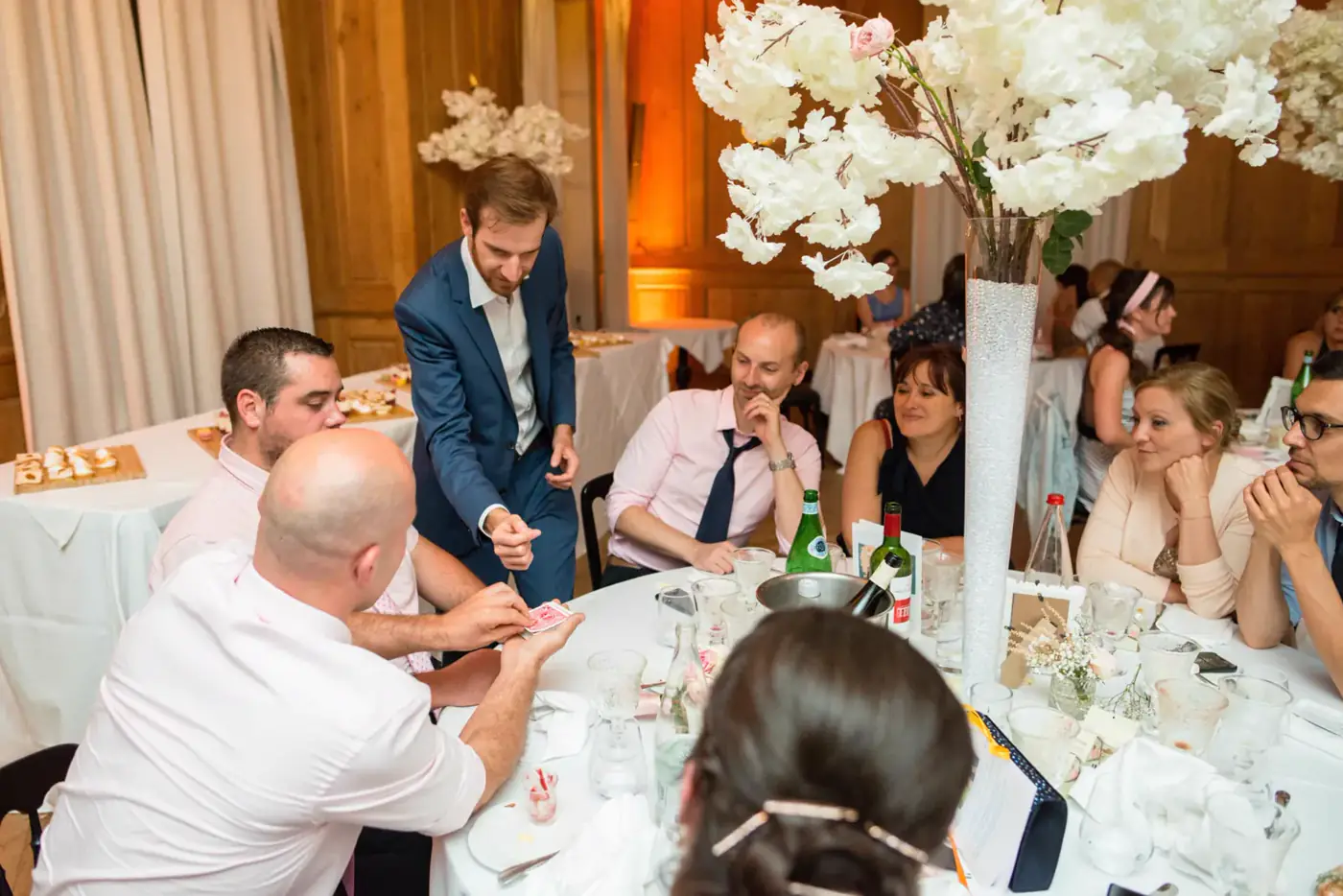 Invités attablés réagissant à un tour de magie pendant un dîner