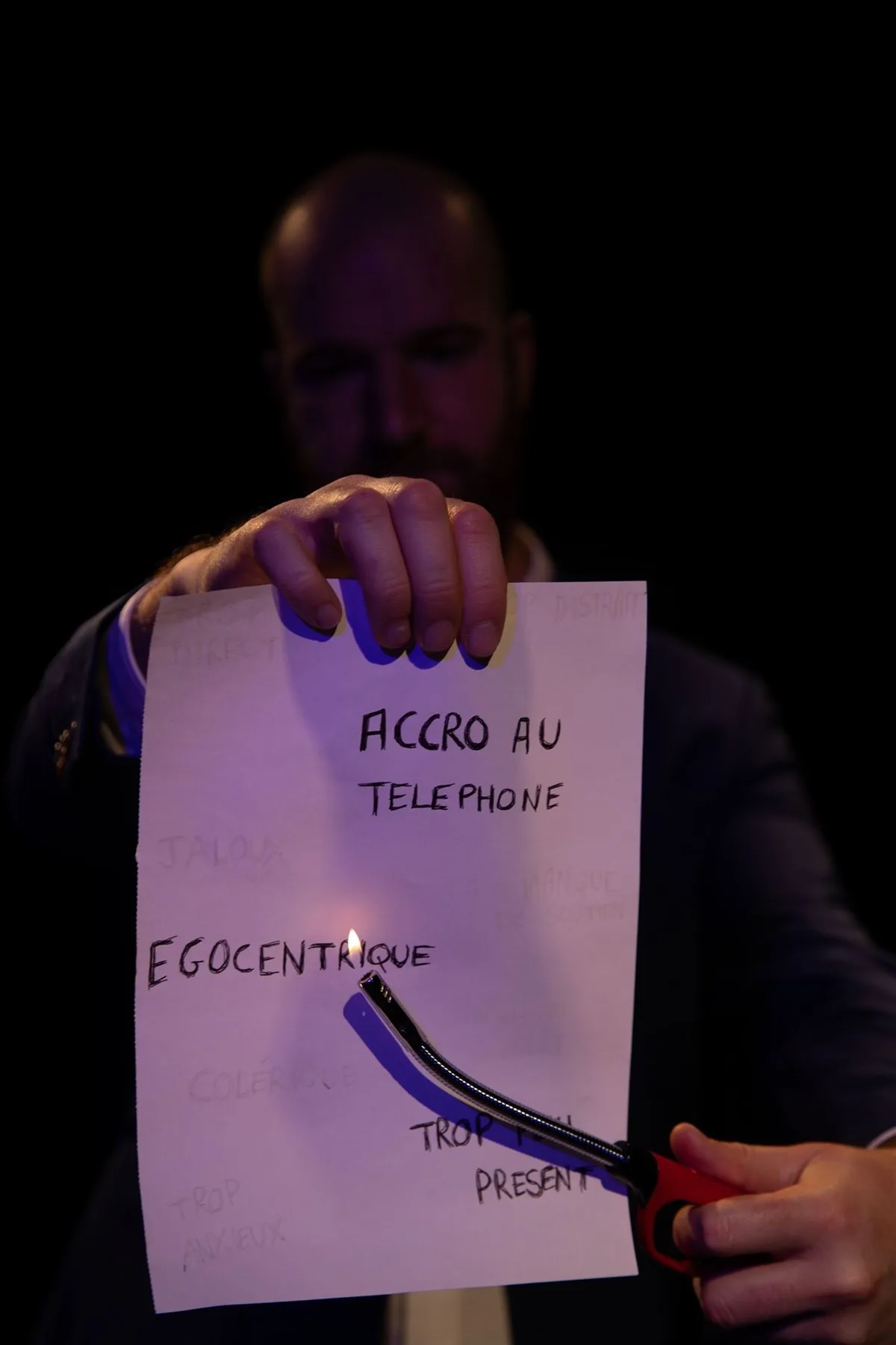 Hugo brûle une feuille où sont écrits des défauts amoureux : accro au téléphone, égocentrique