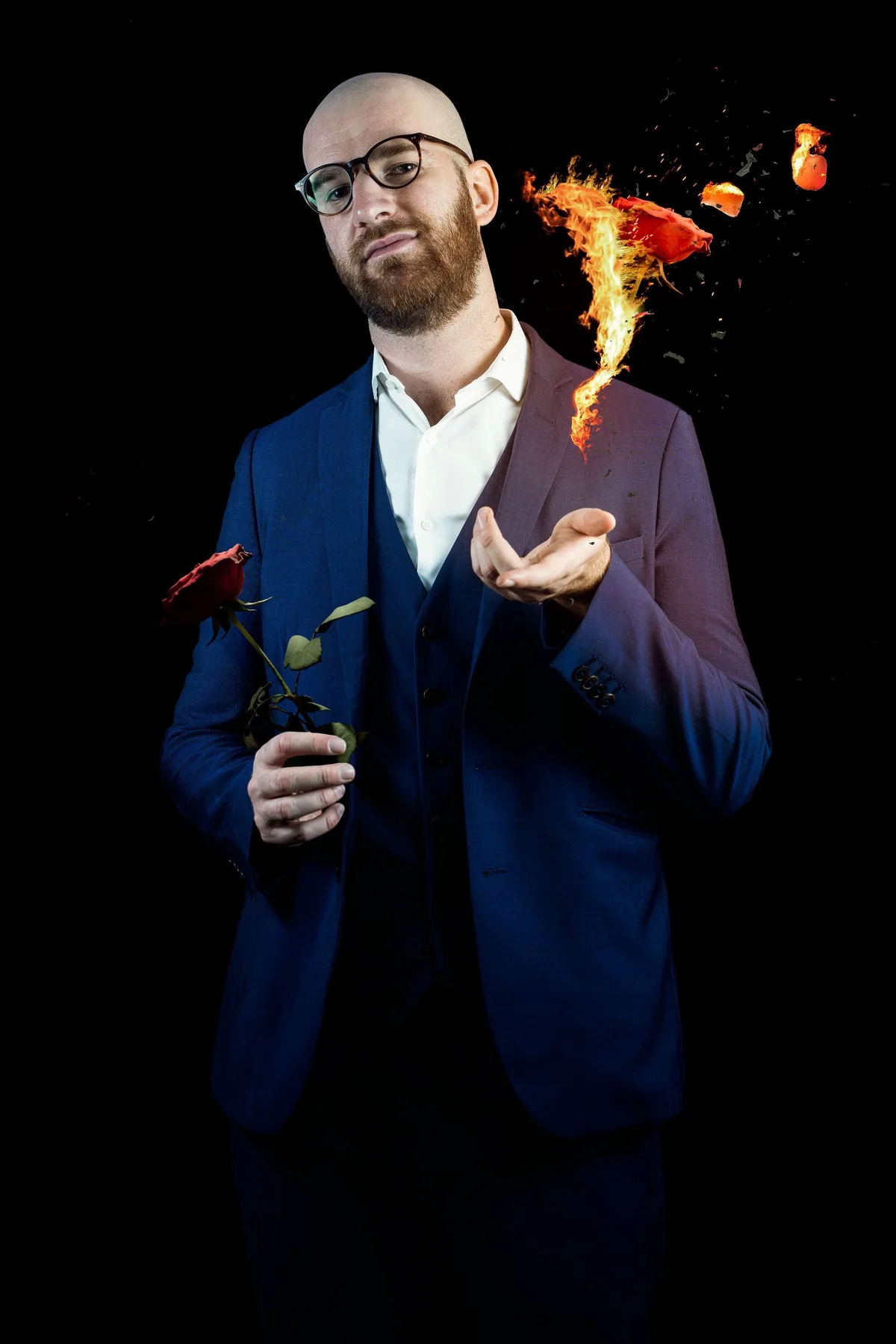 Hugo en costume bleu, une rose à la main, une autre rose qui s'enflamme au-dessus de sa paume